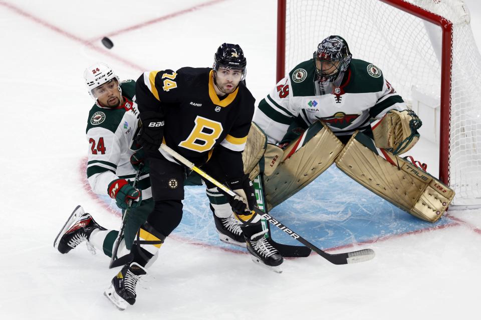 Boston Bruins' Jake DeBrusk (74) and Minnesota Wild's Matt Dumba (24) battle for the puck in front of Wild goalie Marc-Andre Fleury (29) during the first period of an NHL hockey game, Saturday, Oct. 22, 2022, in Boston. (AP Photo/Michael Dwyer)