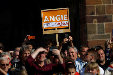 Protesters hold a placard reading: "Angie, no thanks" as German Chancellor Angela Merkel, a top candidate of the Christian Democratic Union Party (CDU) for the upcoming general elections, speaks during an election rally in Fritzlar, Germany September 21, 2017. REUTERS/Kai Pfaffenbach