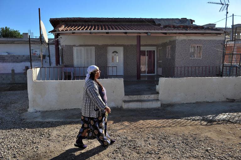 A Roma woman walks next to the house where a child was found with a family that was not hers in Farsala, central Greece, on 19 October, 2013