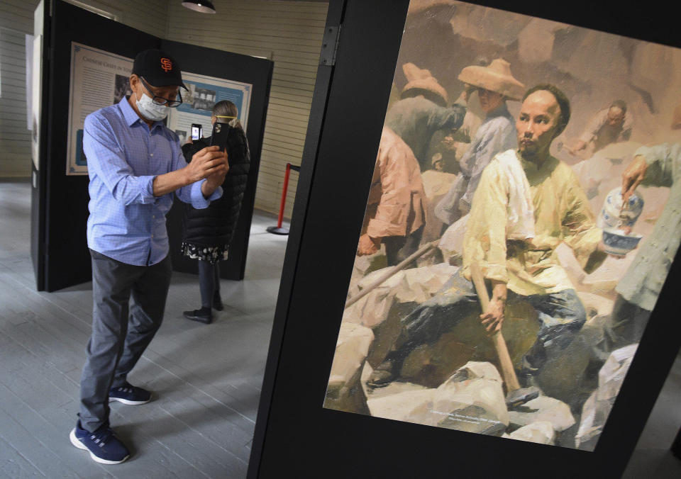 In this Friday, Oct. 1, 2021, photo Ed Hung of San Francisco takes a photo of a Chinese laborer in an exhibit in the restored 1917 Chinese laundry building, after its dedication at Wawona in Yosemite National Park, Calif. Officials unveiled on Friday a new sign and exhibit inside a building originally used as a laundry by Chinese workers at Yosemite's Wawona Hotel, formally recognizing Chinese Americans' contributions to the national park's history. (John Walker /The Fresno Bee via AP)