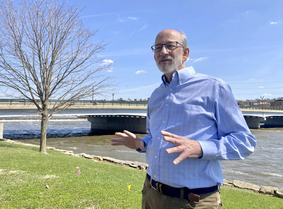 Tom Wadsworth stands on the bank of the Rock River in Dixon, Ill., on Tuesday, April 11, 2023, near the site of the baptismal ceremony on May 4, 1873, when a large crowd gathered on the Truesdell bridge before it toppled over, killing 46 and injuring 56 in the worst road-bridge disaster in American history. Wadsworth's great-grandmother, Gertie Wadsworth, was 3 1/2 years old and was in the arms of her grandmother, Christan Goble, the day the bridge collapsed. Goble died, but Gertie was plucked from the river downstream and revived. (AP Photo/John O'Connor)