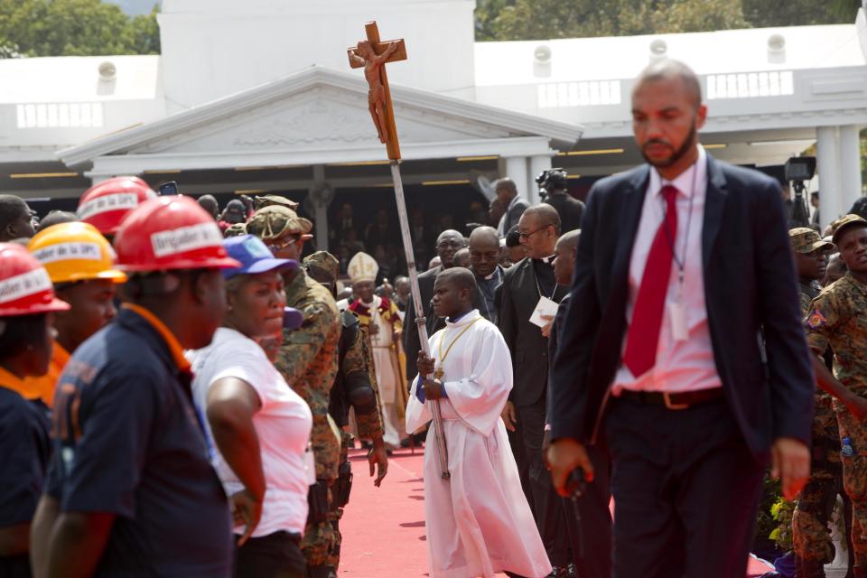 An altar boy carries a cross after a Mass held during the inauguration of of Haiti's new President Jovenel Moise at the National Palace in Port-au-Prince, Haiti, Tuesday Feb. 7, 2017. Moise was sworn as president for the next five years after a bruising two-year election cycle, inheriting a struggling economy and a deeply divided society. (AP Photo/Dieu Nalio Chery)