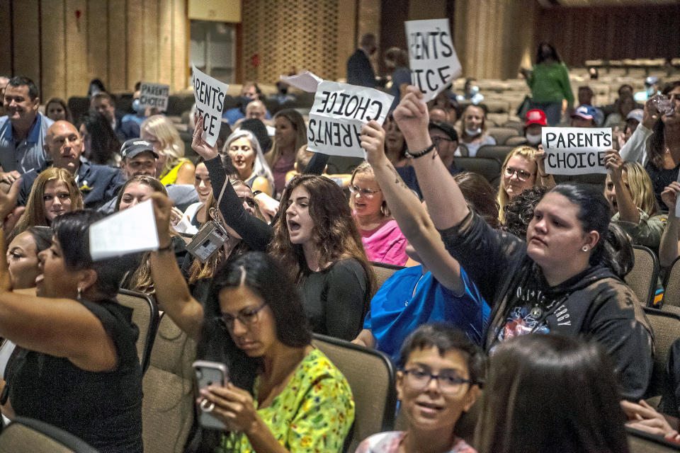 FILE - In this Aug. 25, 2021, file photo, people hold signs and chant during a meeting of the North Allegheny School District school board regarding the district's mask policy, at at North Allegheny Senior High School in McCandless, Pa. A growing number of school board members across the U.S. are resigning or questioning their willingness to serve as meetings have devolved into shouting contests over contentious issues including masks in schools. (Alexandra Wimley/Pittsburgh Post-Gazette via AP, File)