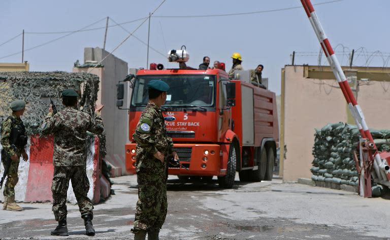 Afghan soldiers gesture as a fire engine leaves a military airport after a rocket attack by suspected Taliban militants in Kabul, on July 3, 2014