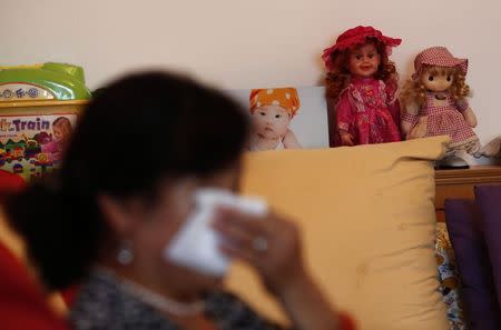 Hu, whose son Zhao's whole family was onboard Malaysia Airlines Flight MH370 which disappeared on March 8, 2014 wipes her tears during an interview with Reuters in Beijing July 24, 2014 as her granddaughter's framed picture is seen in the living room of her house. REUTERS/Kim Kyung-Hoon/Files