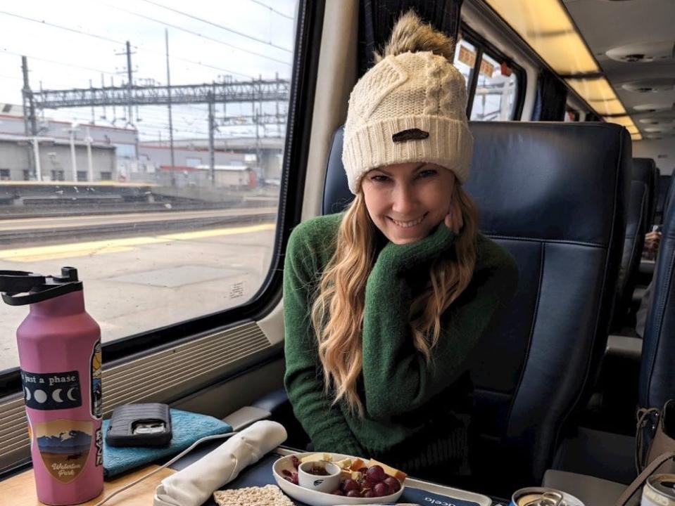Molly O'Brien smiling on a train with a tray of food in front of her 
