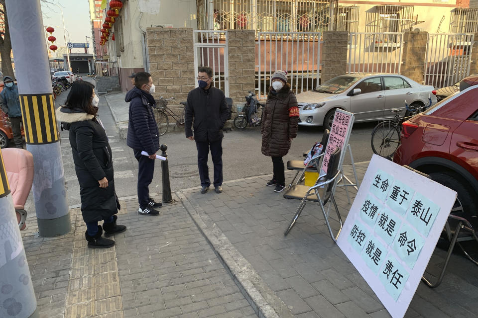 People in face masks stand near a stall to register residents who have recently returned from other provinces in a neighborhood in Beijing, Friday, Jan. 31, 2020. As China institutes the largest quarantine in human history, locking down more than 50 million people in the center of the country, those who have recently been to Wuhan are being tracked, monitored, turned away from hotels and shoved into isolation at their homes and in makeshift quarantine facilities. (AP Photo/Dake Kang)