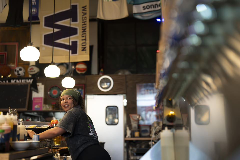 Bartender M.J. Jones looks to the drinks menu while serving a customer at The Sports Bra sports bar on Wednesday, April 24, 2024, in Portland, Ore. (AP Photo/Jenny Kane)