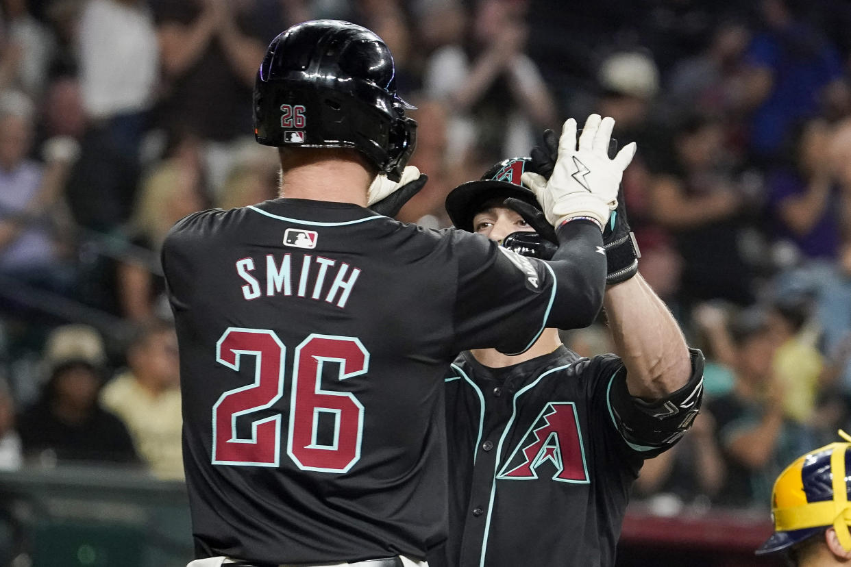 Arizona Diamondbacks' Pavin Smith (26) greets Randal Grichuk, right, at home plate after Grichuk's two-run home run against the Milwaukee Brewers during the seventh inning of a baseball game, Saturday, Sept. 14, 2024, in Phoenix. (AP Photo/Darryl Webb)