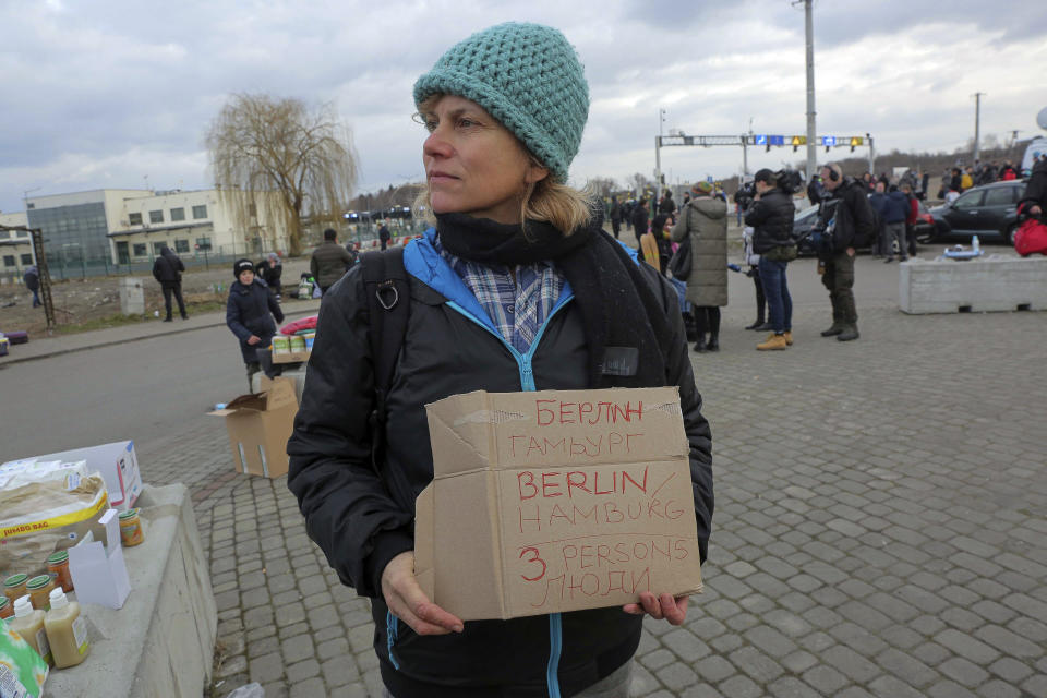 German Tanja Shwarcz, 51, holds a sign offering shelter in Hamburg, Germany to Ukrainian refugees arriving at the Medyka border crossing, Poland, Saturday, Feb. 26, 2022. (AP Photo/Visar Kryeziu)