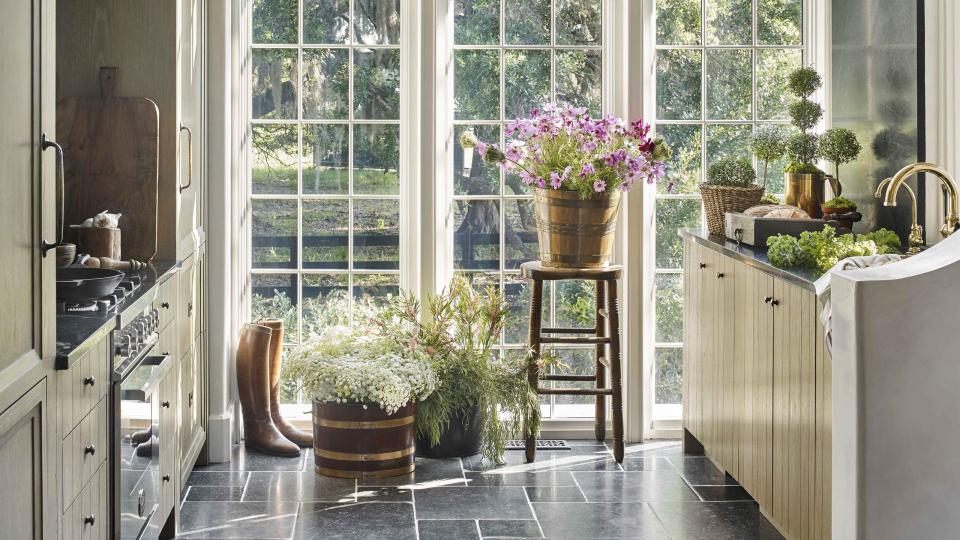 a wall of windows brings in natural light to a galley kitchen with stone countertops and floors