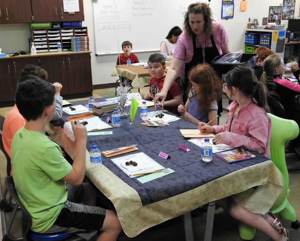 Amy Unkefer, third grade teacher at Coshocton Elementary School, passes out grapes to students during a book tasting activity. Kaitlyn Ashbrook, director of Curriculum and Federal Programming for Coshocton City Schools, said the reading taste and other creative initiatives are key into encouraging reading among youth. The district also had a recent Family Reading Night and sponsored Little Free Libraries.