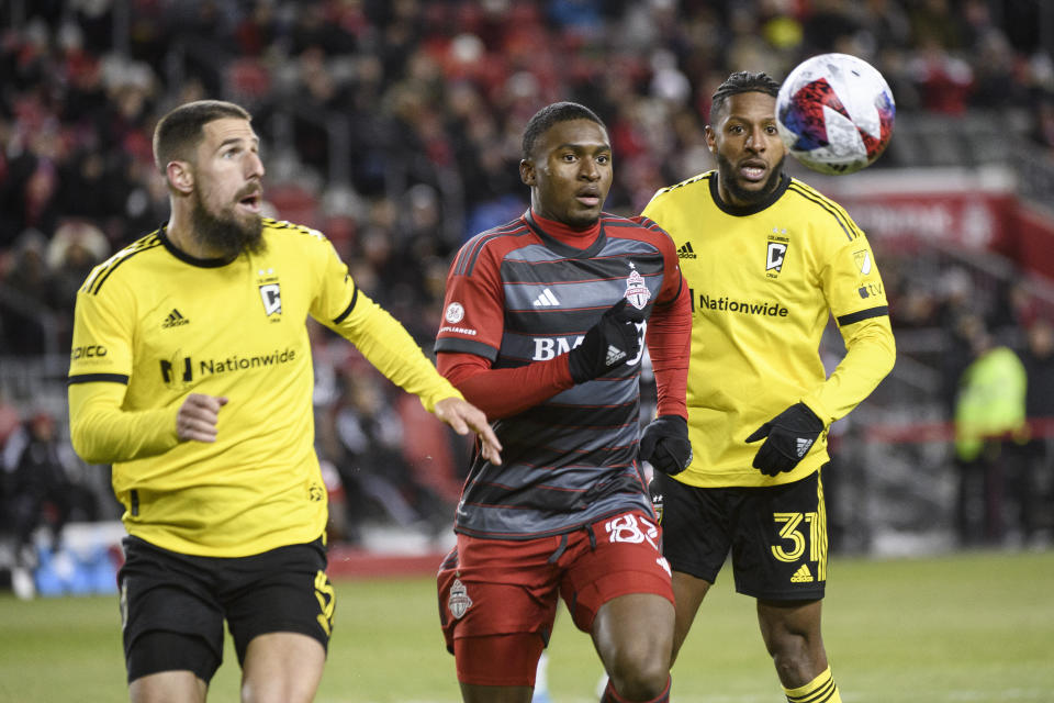 Toronto FC forward Hugo Mbongue (83) and Columbus Crew defenders Milos Degenek (5) and Columbus Crew Steven Moreira (31) chase the ball during the second half of an MLS soccer match Saturday, March 11, 2023, in Toronto. (Christopher Katsarov/The Canadian Press via AP)
