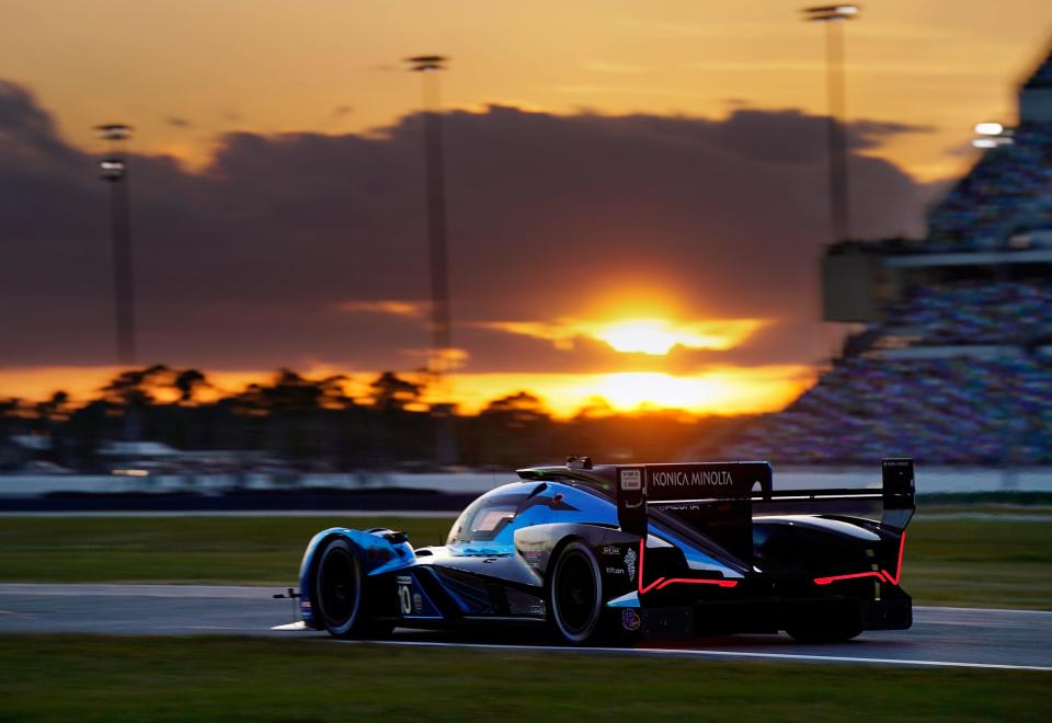 Cars race against the backdrop of a beautiful sunset during the Rolex 24 at Daytona International Speedway.