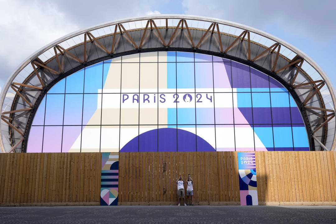 Turistas toman fotos en la Arena del Campo de Marte, el miércoles 24 de julio de 2024, previo a los Juegos Olímpicos de París. (AP Foto/Eugene Hoshiko)