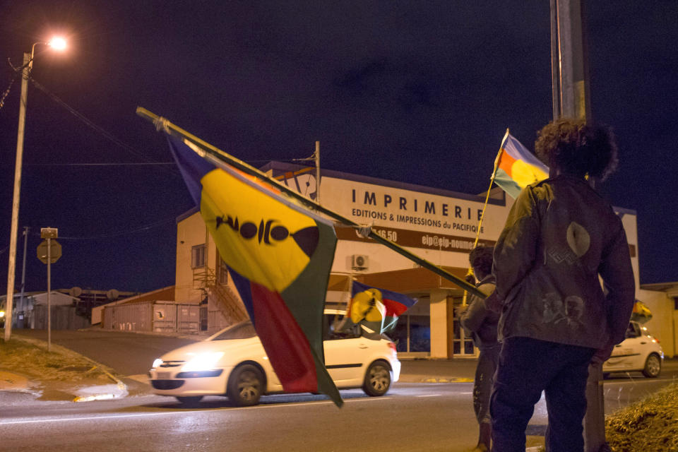 Pro-independentists celebrate in the streets of Noumea, the New Caledonia's capital, as they wave the indigenous Malanesian flag called the 'Kanak' flag after official results gave 43.6 percent support for independence as part of the referendum, Sunday, Nov. 4, 2018. A majority of voters in the South Pacific territory of New Caledonia chose to remain part of France instead of backing independence, election officials announced Sunday as French President Emmanuel Macron promised a full dialogue on the region's future. (AP Photo/Mathurin Derel)