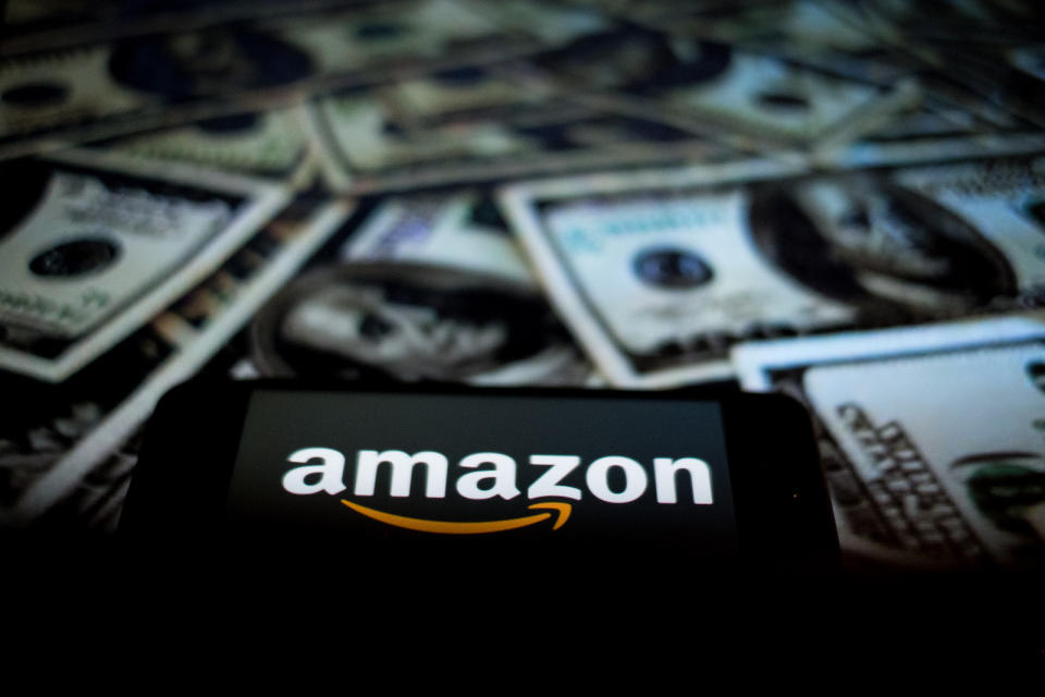 In this photographic illustration, the Amazon logo is displayed on the screen of a smartphone as a background to the Dollars on a computer person   on April 29, 2021 in Rome, Italy. (Photo by Andrea Ronchini/NurPhoto)