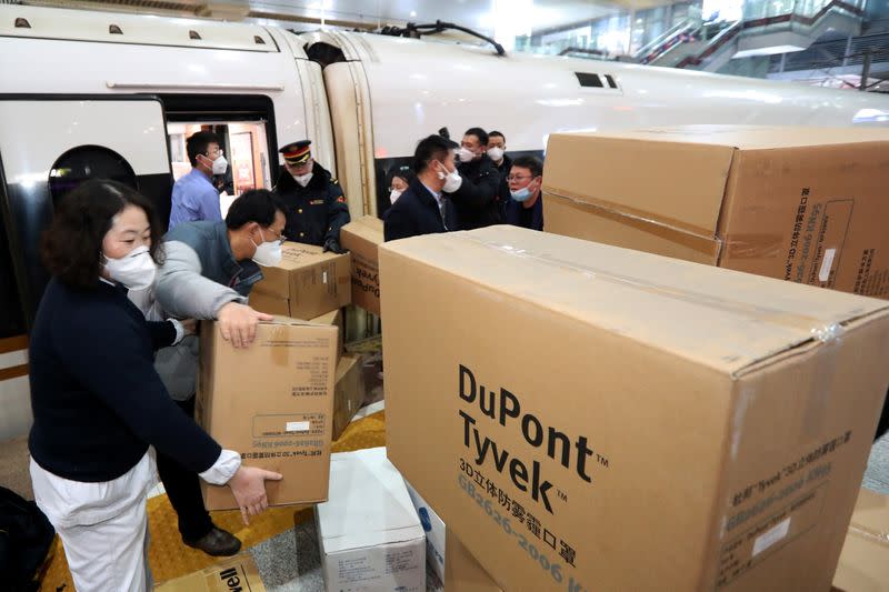 Medical and railway station staff members load boxes of protective masks and other supplies onto a train as a team of medical professionals from Jiangsu province departs to provide aid to Wuhan, at Nanjing Railway Station