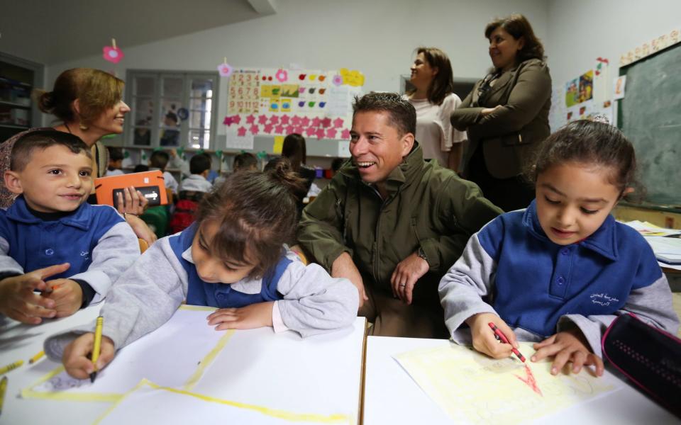 Tom Fletcher, global strategy director for Theirworld and the Global Business Coalition for Education (former British Ambassador to Lebanon), sits with Syrian refugee children inside a classroom in Mtein Public School - Credit: Reuters