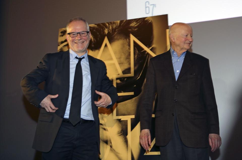 Cannes Film Festival general delegate Thierry Fremaux, left, and Festival President Gilles Jacob, right, pose next to the poster of the Festival, at the end of a press conference to announce this years line up in Paris, Thursday April 17, 204. A Tommy Lee Jones western and a David Cronenberg exposé on Hollywood are among the 18 films vying for the top prize at the Cannes Film Festival. The festival organizers also said Thursday that two women directors and famed New Wave filmmaker Jean-Luc Godard will be in competition at the festival that runs May 14-25. (AP Photo/Remy de la Mauviniere)