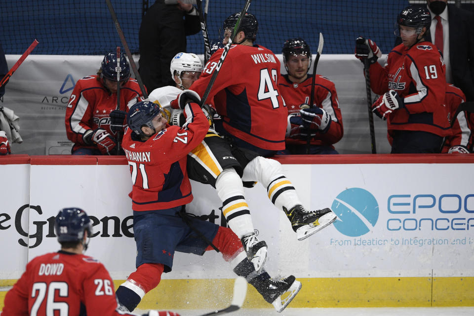 Washington Capitals right wing Garnet Hathaway (21) checks Pittsburgh Penguins defenseman Mike Matheson, center, during the third period of an NHL hockey game, Thursday, Feb. 25, 2021, in Washington. Capitals right wing Tom Wilson (43) looks on. (AP Photo/Nick Wass)