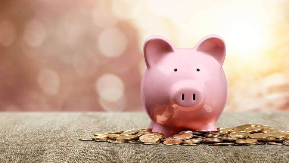 Hand Putting a Coin in Piggy Bank.