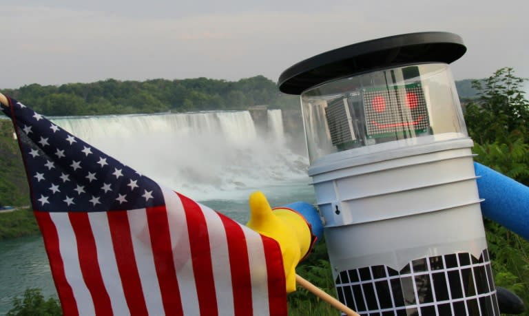 This undated photo courtesy of hitchBOT shows hitchBOT posing with the US flag at Niagra Falls