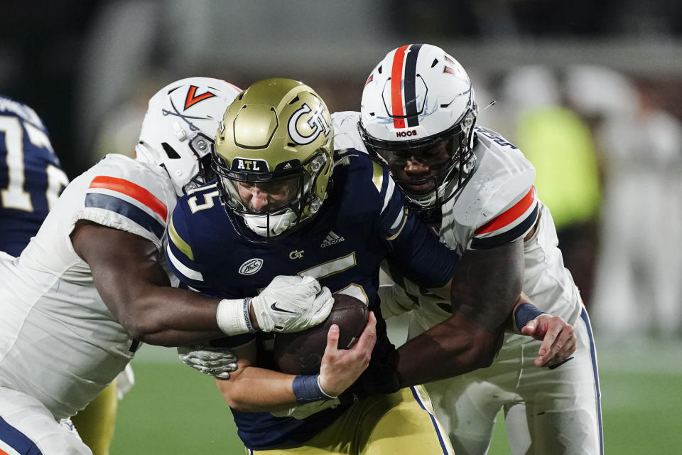 Georgia Tech quarterback Zach Gibson (15) is sacked by Virginia's Chico Bennett Jr., right, and Olasunkonmi Agunloye during the second second half of an NCAA college football game Thursday, Oct. 20, 2022, in Atlanta. (AP Photo/John Bazemore)