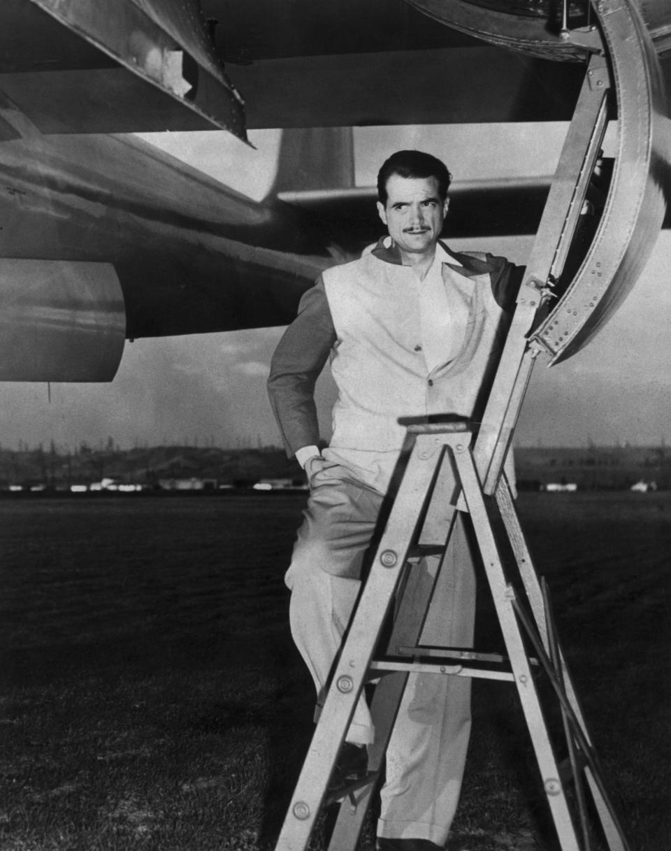 Howard Hughes poses at entry hatch of one of his airplanes in 1947.