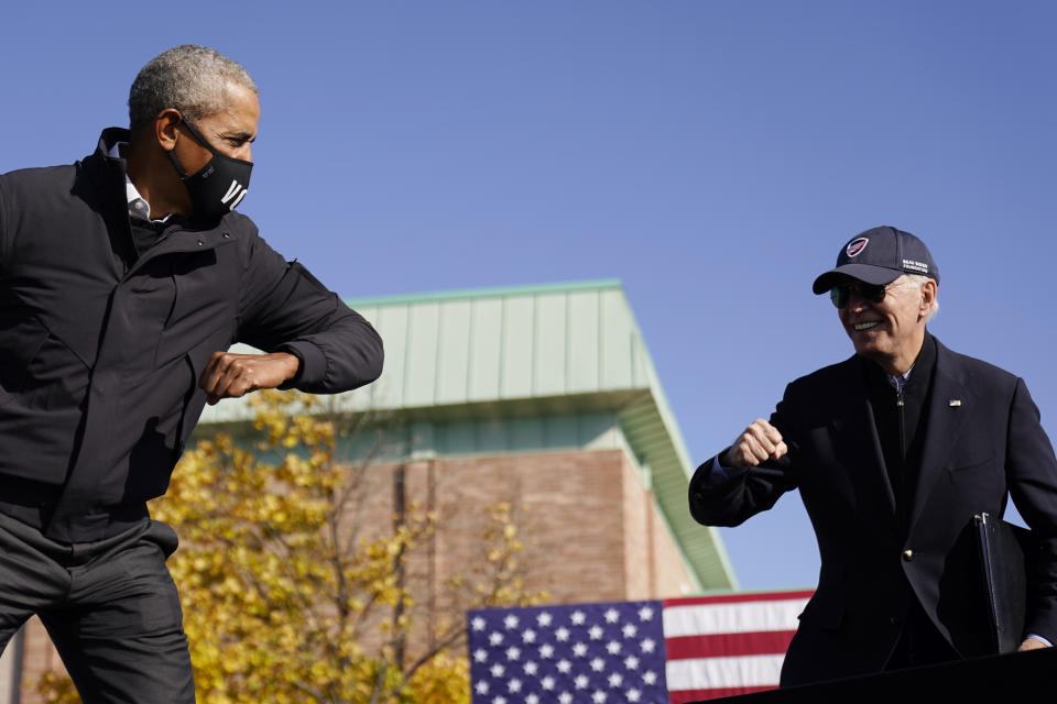 Democratic presidential candidate former Vice President Joe Biden, right, and former President Barack Obama greet each other with an air elbow bump, at the conclusion of rally at Northwestern High School in Flint, Mich., Saturday, Oct. 31, 2020. (AP Photo/Andrew Harnik)