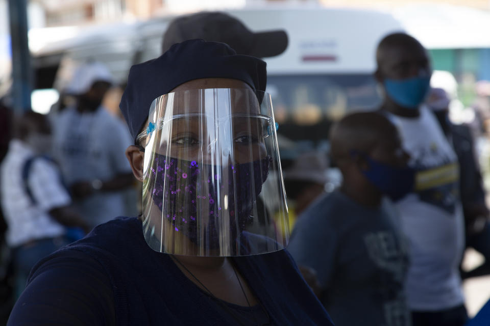 FILE — In this Thursday, Dec. 24, 2020 file photo people wear face masks to protect against COVID-19 before boarding a minibus taxi in Johannesburg. In a television address to the nation Monday, Dec. 28, 2020, President Cyril Ramaphosa announced that the country would revert to level 3 of a strict lockdown in a bid to control a surge in the virus and it would be compulsory to wear face masks in public. (AP Photo/Denis Farrell/File)