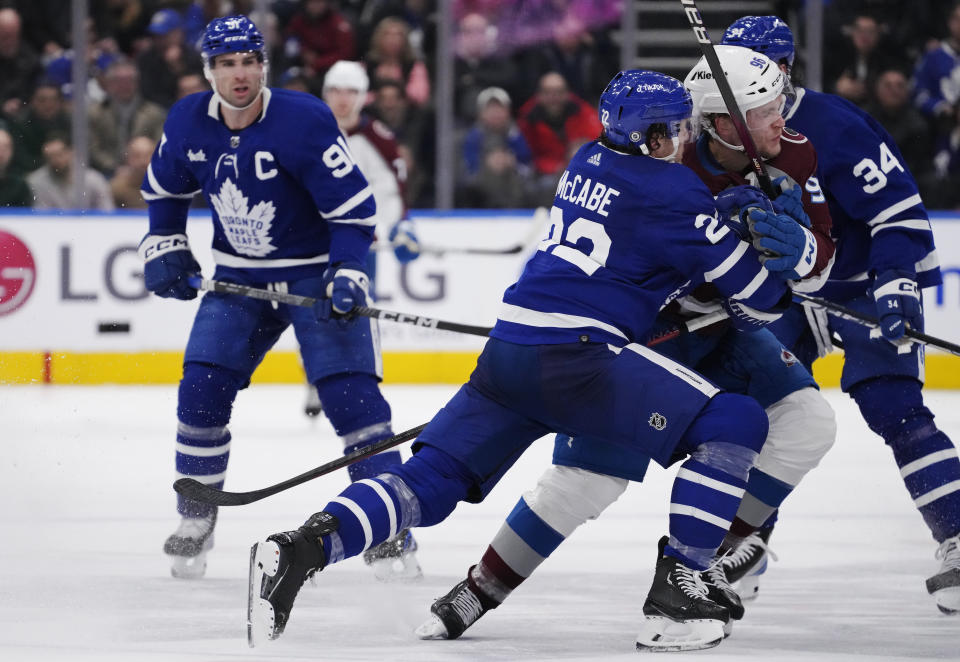 Toronto Maple Leafs' Jake McCabe (22) checks Colorado Avalanche's Mikko Rantanen (96) into Maple Leafs' Auston Matthews (34) as John Tavares (91) watches during the third period of an NHL hockey game Wednesday, March 15, 2023, in Toronto. (Frank Gunn/The Canadian Press via AP)