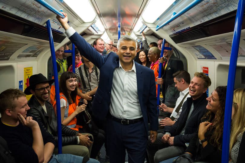 London Mayor Sadiq Khan stands between passengers in the first Night Tube train