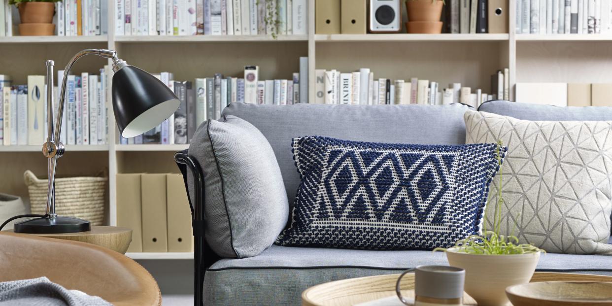 grey sofa and carpet in living room with stacked bookcase