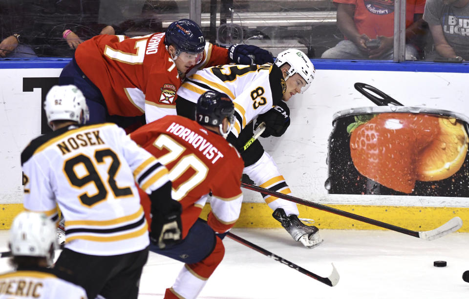 Boston Bruins right wing Karson Kuhlman (83) and Florida Panthers left wing Frank Vatrano (77) battle for possession during the second period of an NHL hockey game Wednesday, Oct. 27, 2021, in Sunrise, Fla. (AP Photo/Jim Rassol)