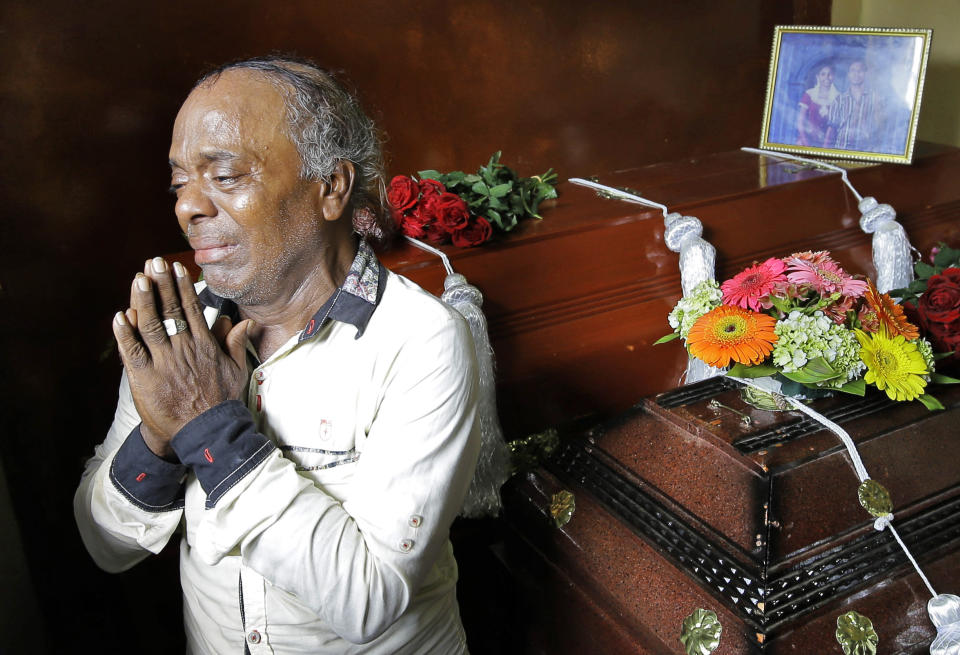Baby Joseph Gomes prays standing next to coffins of his family members killed in the Easter Sunday bombings in Colombo, Sri Lanka, Tuesday, April 23, 2019. Gomes lost five members of his family. The six near-simultaneous attacks on three churches and three luxury hotels and three related blasts later Sunday were the South Asian island nation's deadliest violence in a decade while Sri Lanka police arrested 40 suspects in the wake of a state of emergency that took effect Tuesday giving the military war-time powers. (AP Photo/Eranga Jayawardena)