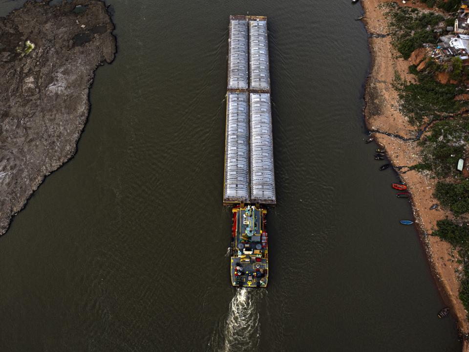 Barges loaded with cement navigate the channel between the beach and an ancient extinct volcano, exposed by the low level of the Paraguay river, in Asuncion amid a historic drought that is affecting the its level, in Paraguay, Wednesday, Sept. 22, 2021. (AP Photo/Jorge Saenz)