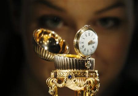 An assistant poses for a photograph with a Faberge egg during a photo-call at antique dealer Wartski, in central London April 7, 2014. REUTERS/Olivia Harris