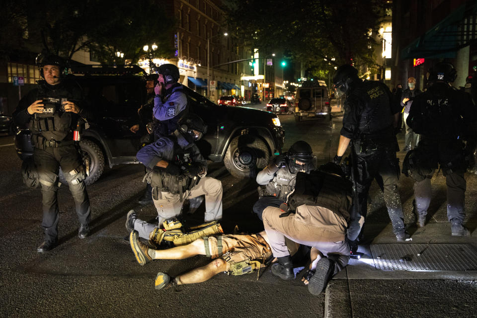 FILE - In this Aug. 29, 2020, file photo, a man who later died is treated after being shot at a demonstration in Portland, Ore. Once hailed as one of the most livable cities in the U.S., Portland, Oregon, is grappling with an uncertain future as it reaches a stunning benchmark: 100 consecutive nights of racial injustice protests marred by vandalism, chaos — and now, the killing of a supporter of President Donald Trump. (AP Photo/Paula Bronstein, File)