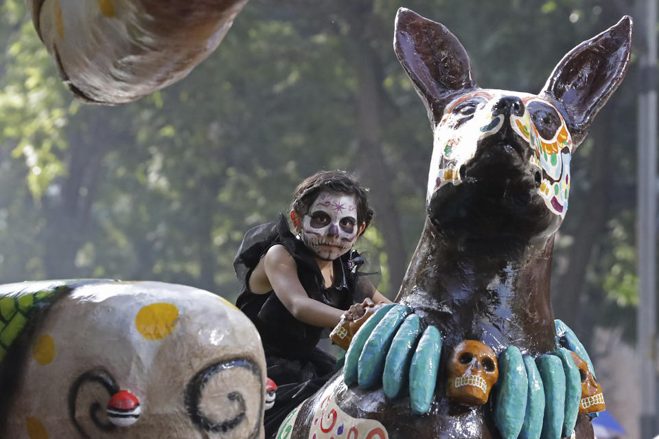 A child rides on a float during a James Bond-inspired Day of the Dead Parade, in Mexico City, Saturday, Nov. 4, 2023. The Hollywood-style parade was adopted in 2016 by Mexico City to mimic a fictitious march in the 2015 James Bond movie “Spectre.” (AP Photo/Ginnette Riquelme)