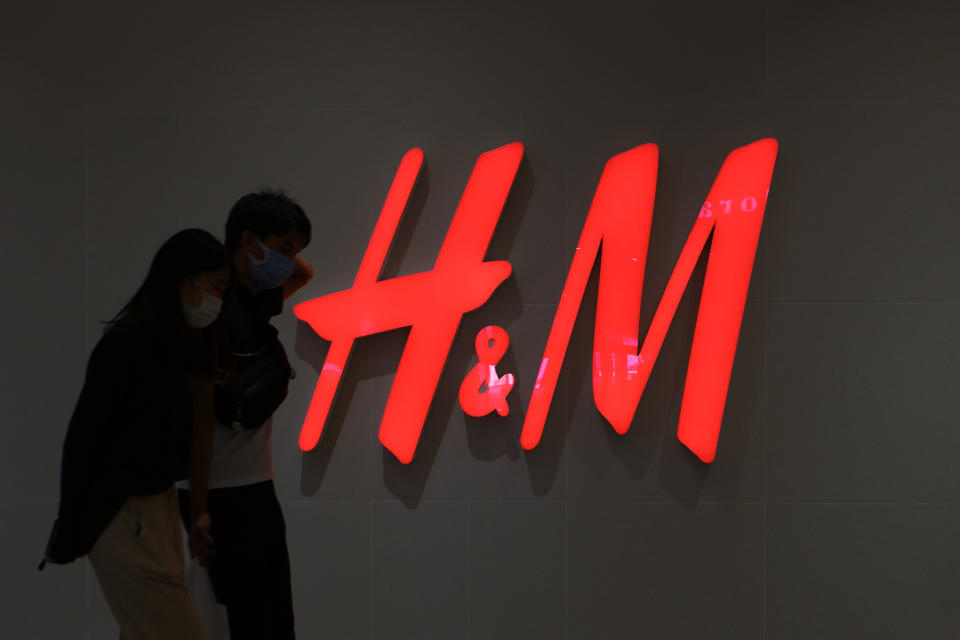 TOKYO, JAPAN - 2020/10/11: A couple wearing facemasks walks past an H&M logo and Clothing retail store in Tokyo. (Photo by James Matsumoto/SOPA Images/LightRocket via Getty Images)