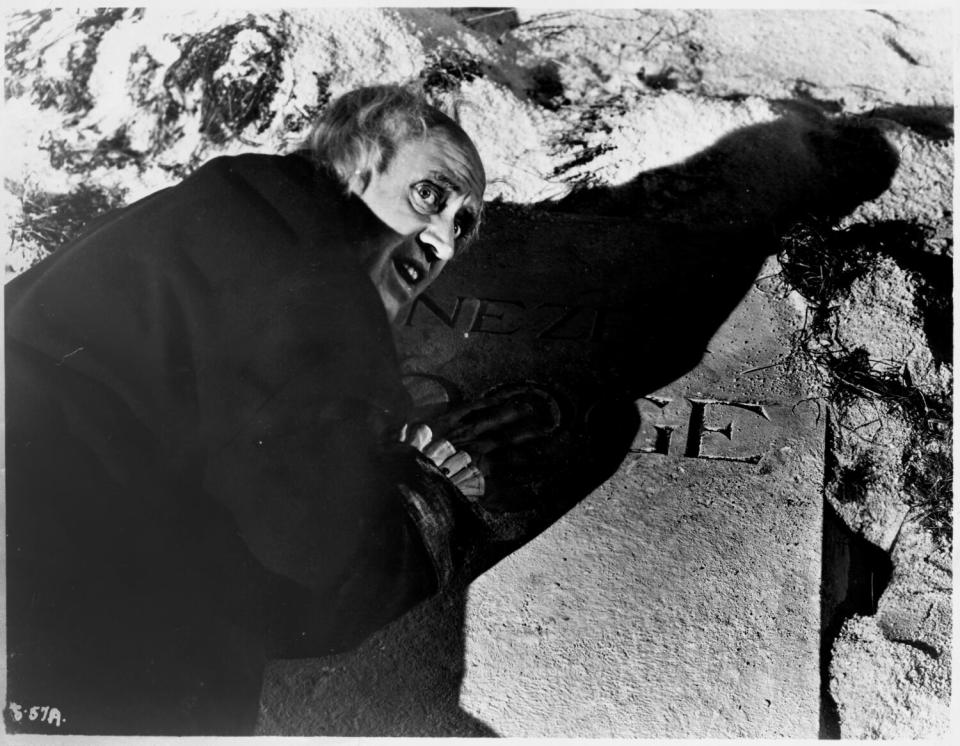 Ebenezer Scrooge (Alastair Sim) leans on his own grave marker in "A Christmas Carol" (1951)