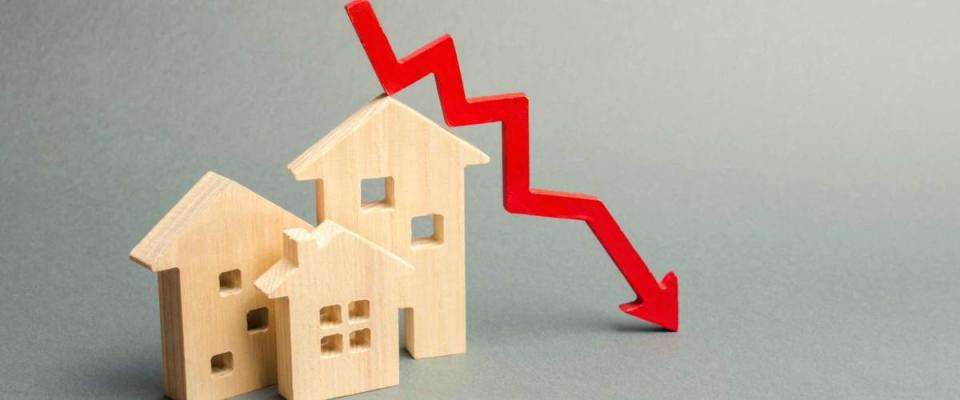 Miniature wooden houses and a red arrow down, signifying low mortgage rates