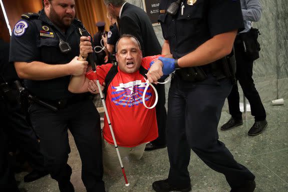 Capitol police drag a blind protestor out of the hearing.