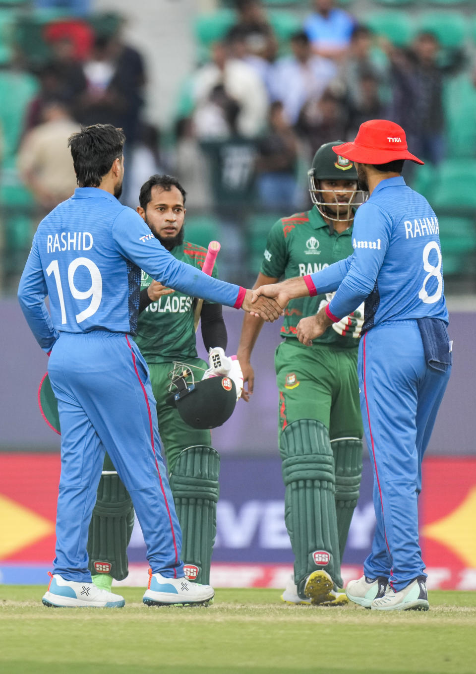 Bangladesh's Najmul Hossain Shanto, second right and Mushfiqur Rahim are congratulated by Afghanistan's Rashid Khan and Rahmat Shah after they won the ICC Cricket World Cup match between Afghanistan and Bangladesh in Dharamsala, India, Saturday, Oct.7, 2023. (AP Photo/Ashwini Bhatia)
