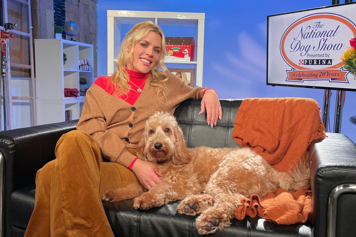 Busy Phillips sits on a couch with her dog, Gina