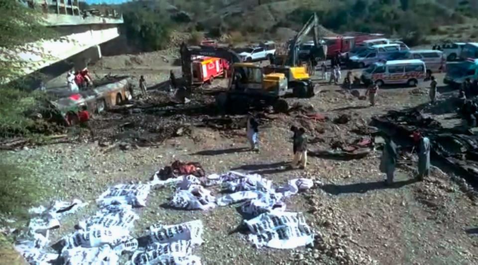 Rescue workers collect bodies from the burnt wreckage of a bus accident in Bela, an area of Lasbela district of Balochistan province (AP)