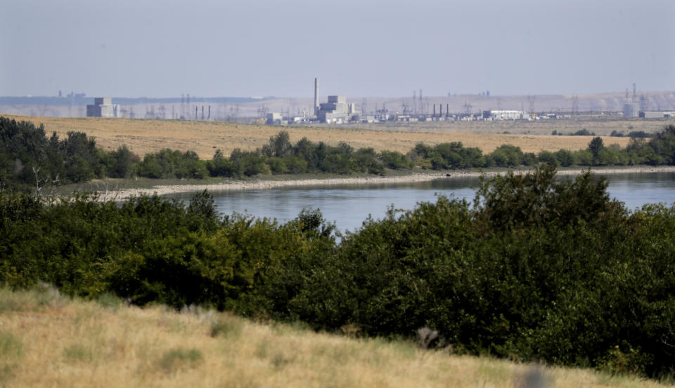 FILE - In this Aug. 14, 2019 photo, buildings on the Hanford Nuclear Reservation along the Columbia River are seen from the Hanford Reach National Monument near Richland, Wash. The location is featured in a collection of mini-essays by American writers published online by the Frommer's guidebook company about places they believe helped shape and define America. (AP Photo/Elaine Thompson, File)