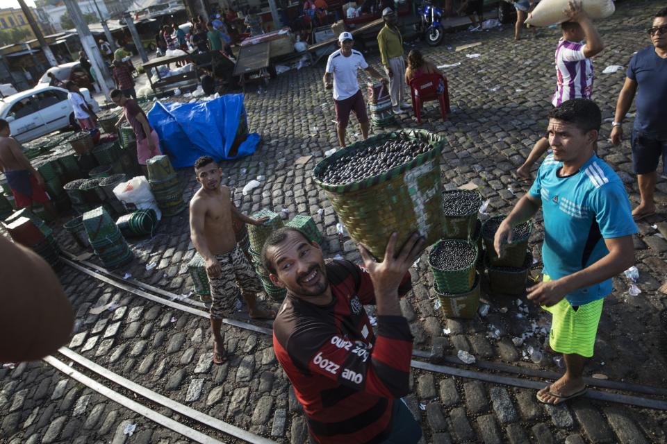 In this Sept. 7, 2019 photo, workers load a truck with acai berries at the Ver-o-Peso riverside market in Belém, Brazil. Abroad, acai is best-known in its frozen pulp form for juice and smoothies. But here, at the market, the local way is to eat it like a soup. (AP Photo/Rodrigo Abd)