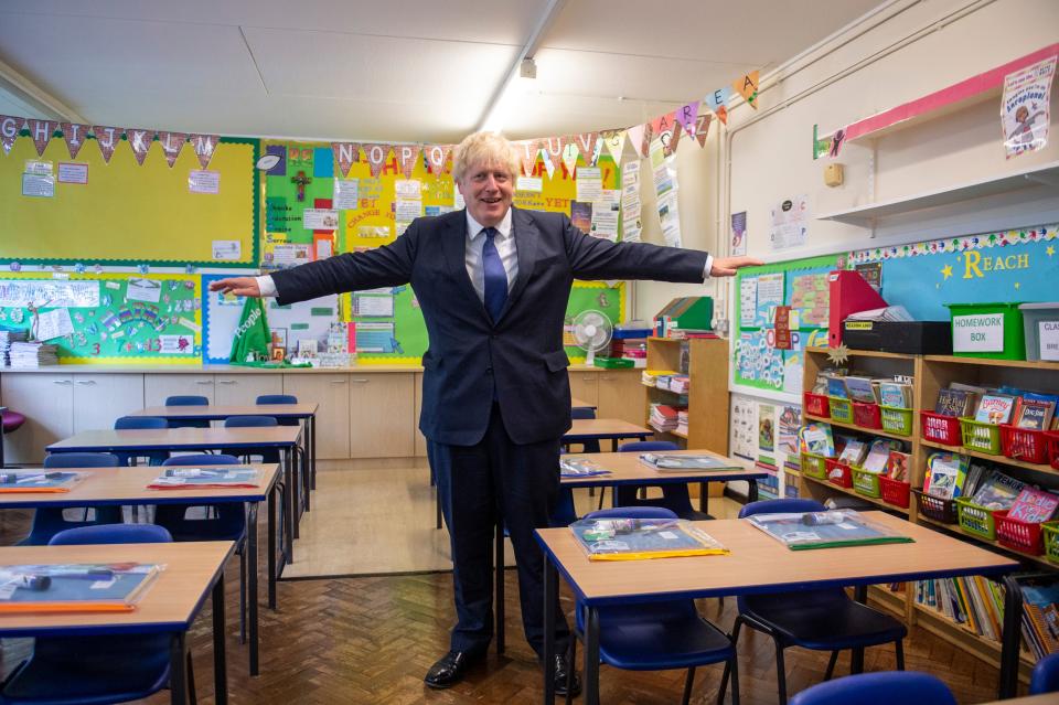 Britain's Prime Minister Boris Johnson poses with his arms out-stretched in a classroom as he visits St Joseph's Catholic Primary School in Upminster, east London, on August 10, 2020 to see preparedness plans implemented ahead of the start of the new school year as a response to the novel coronavirus pandemic. (Photo by Lucy YOUNG / POOL / AFP) (Photo by LUCY YOUNG/POOL/AFP via Getty Images)